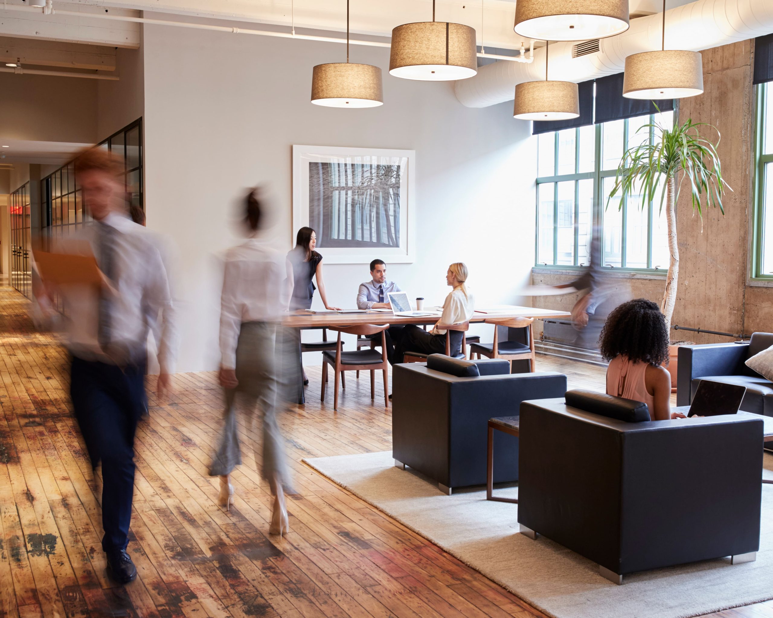 Oficina moderna con empleados trabajando y moviéndose, creando un ambiente dinámico y colaborativo.
